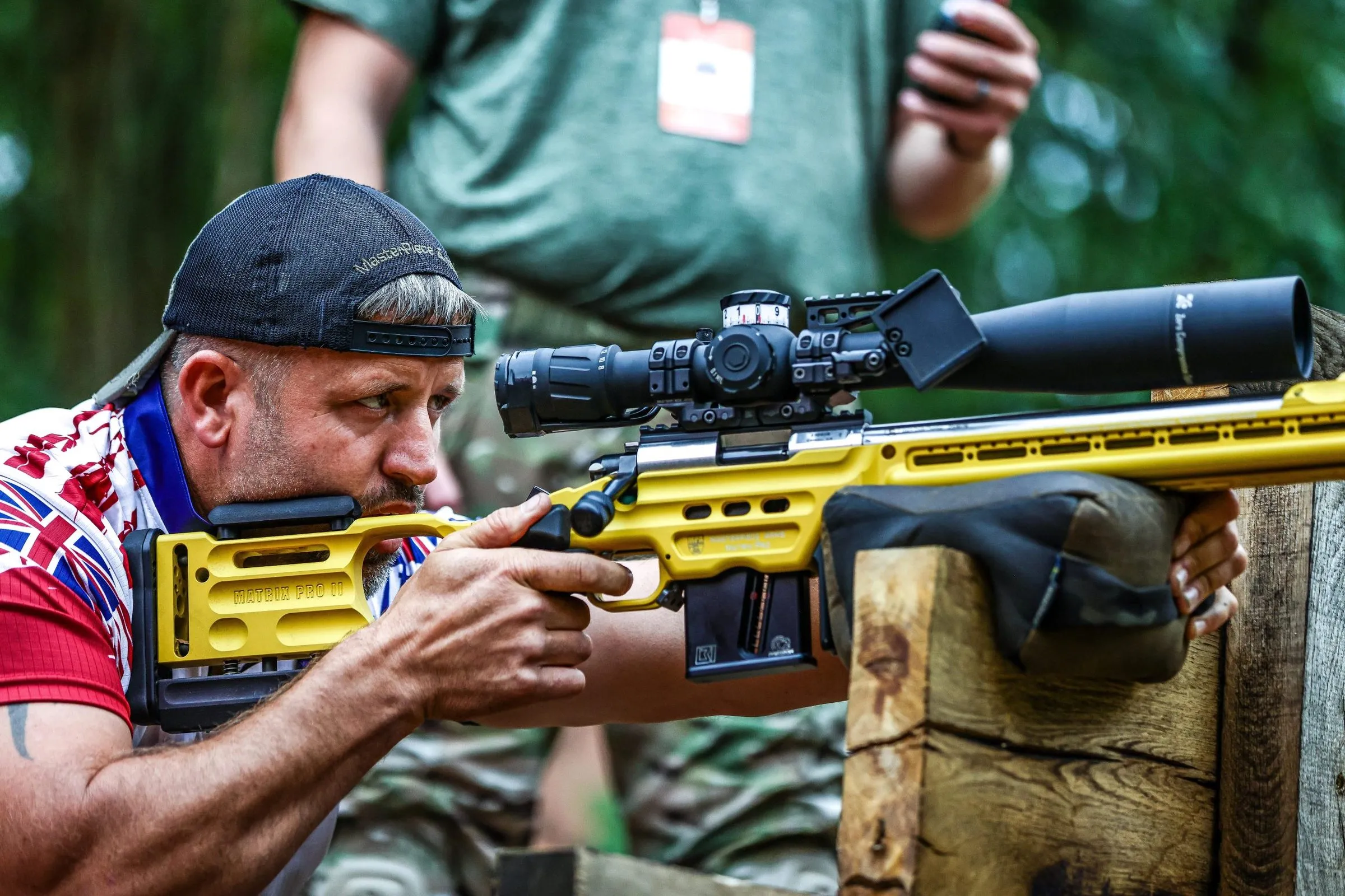 Josh Martin behind a yellow MasterPiece Arms Matrix Pro II rifle in a Team GB jersey at the IPRF Rimfire World Championships